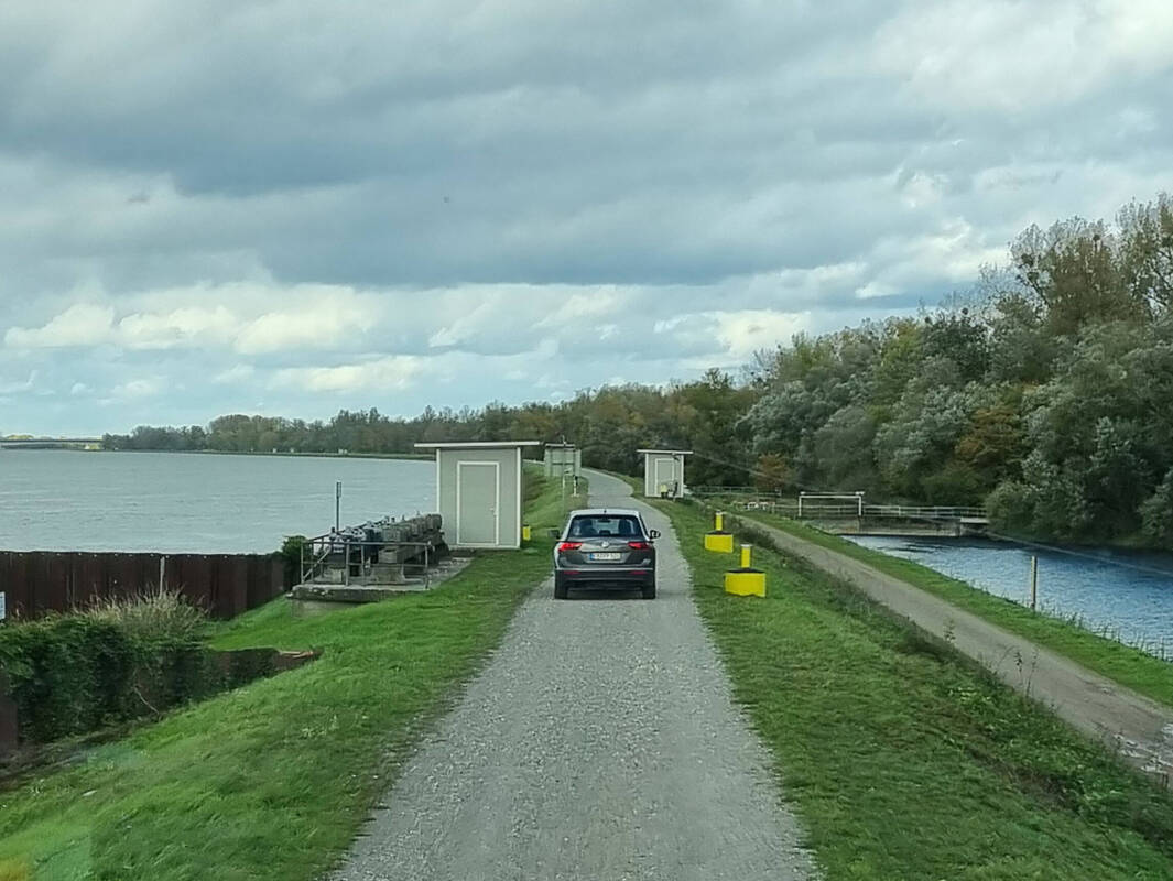Auf dem Einlassbauwerk mit dem Rhein auf der linken und dem Rückhalteraum auf der rechten Seite des Dammes.